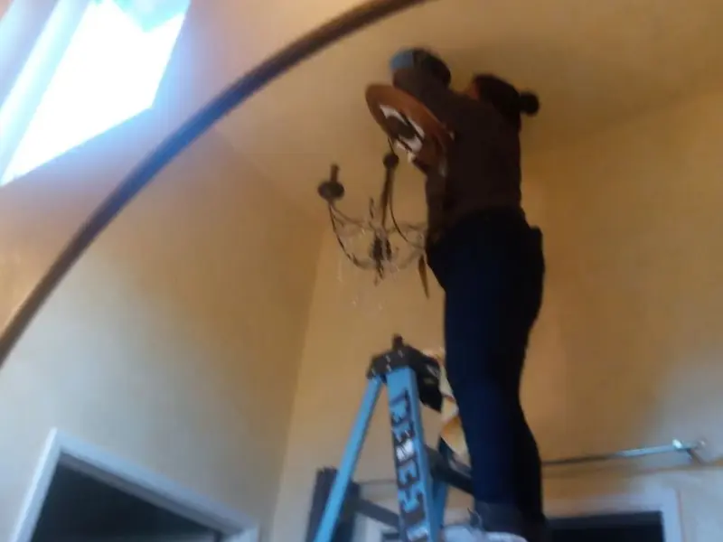 Electrician installing a chandelier in a Honey Brook residence